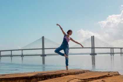 photo of woman standing on rock formation doing yoga